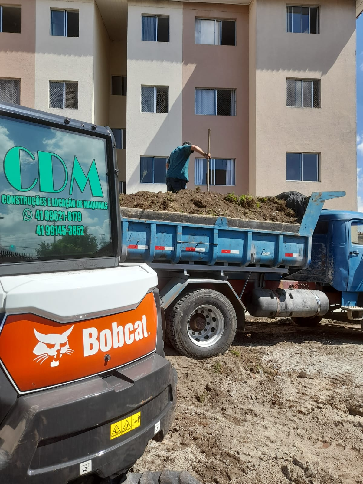 Equipe da CDM com mini escavadeira Bobcat e caminhão caçamba em obra
