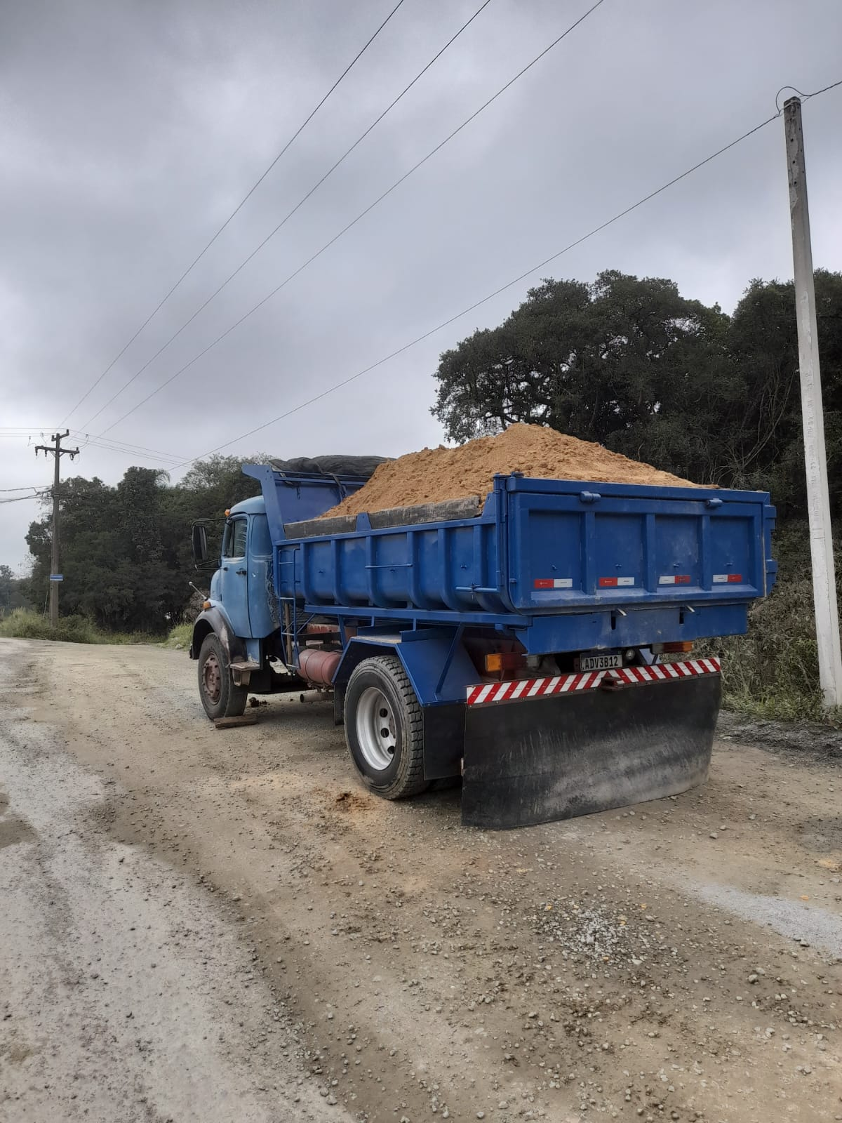 Caminhão caçamba azul de 7 m³ carregado com areia